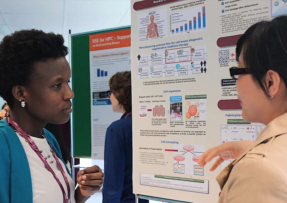 Two engineers chatting in front of a poster.