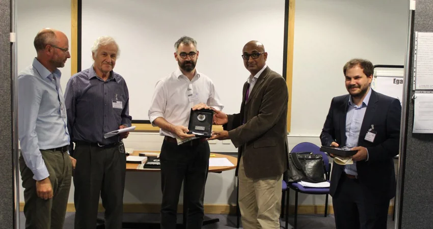 Group of male academics. An award is presented to one of them