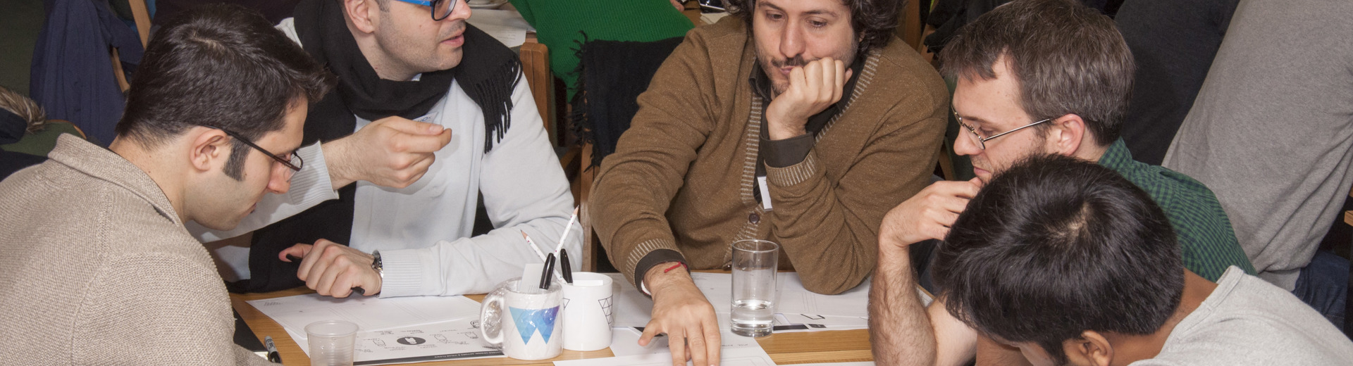 Tables of groups of academics discussing and working together