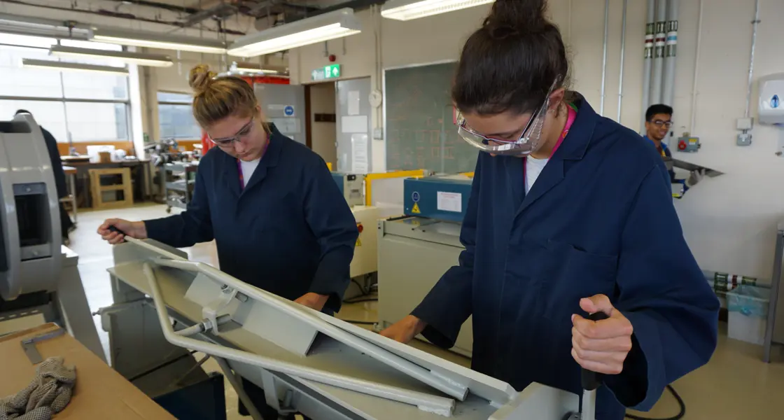 Two students in lab with labcoats and safety glasses