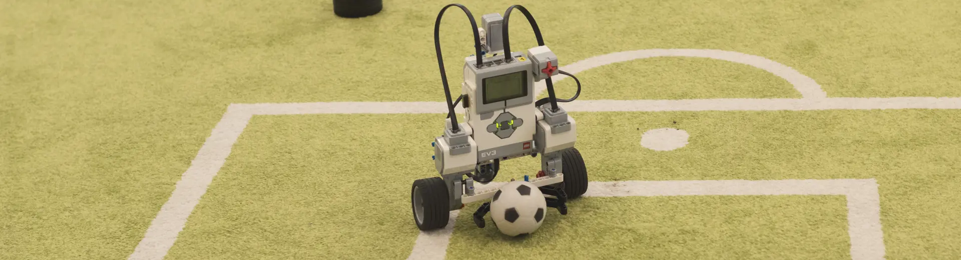 Small robot playing football on miniature football pitch
