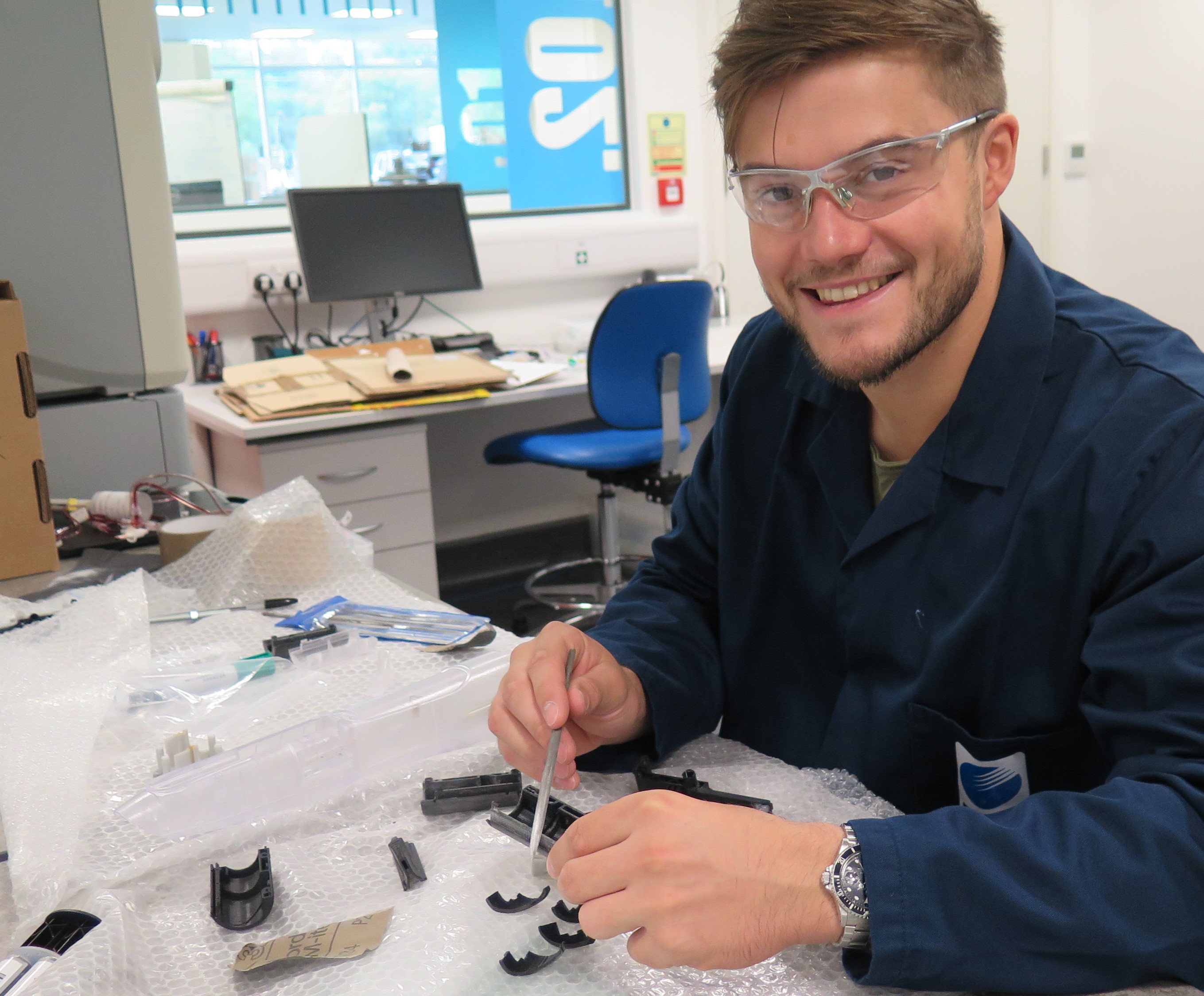 Man smiling wearing safety glasses and lab coat
