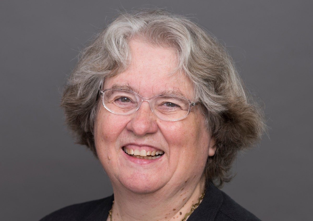 Woman smiling with short grey hair and glasses
