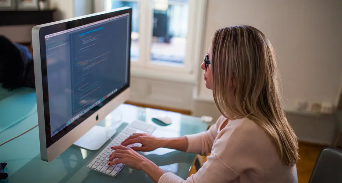 Blonde woman working at a white computer