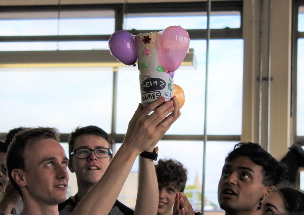 Group of school students, one holds up balloon project