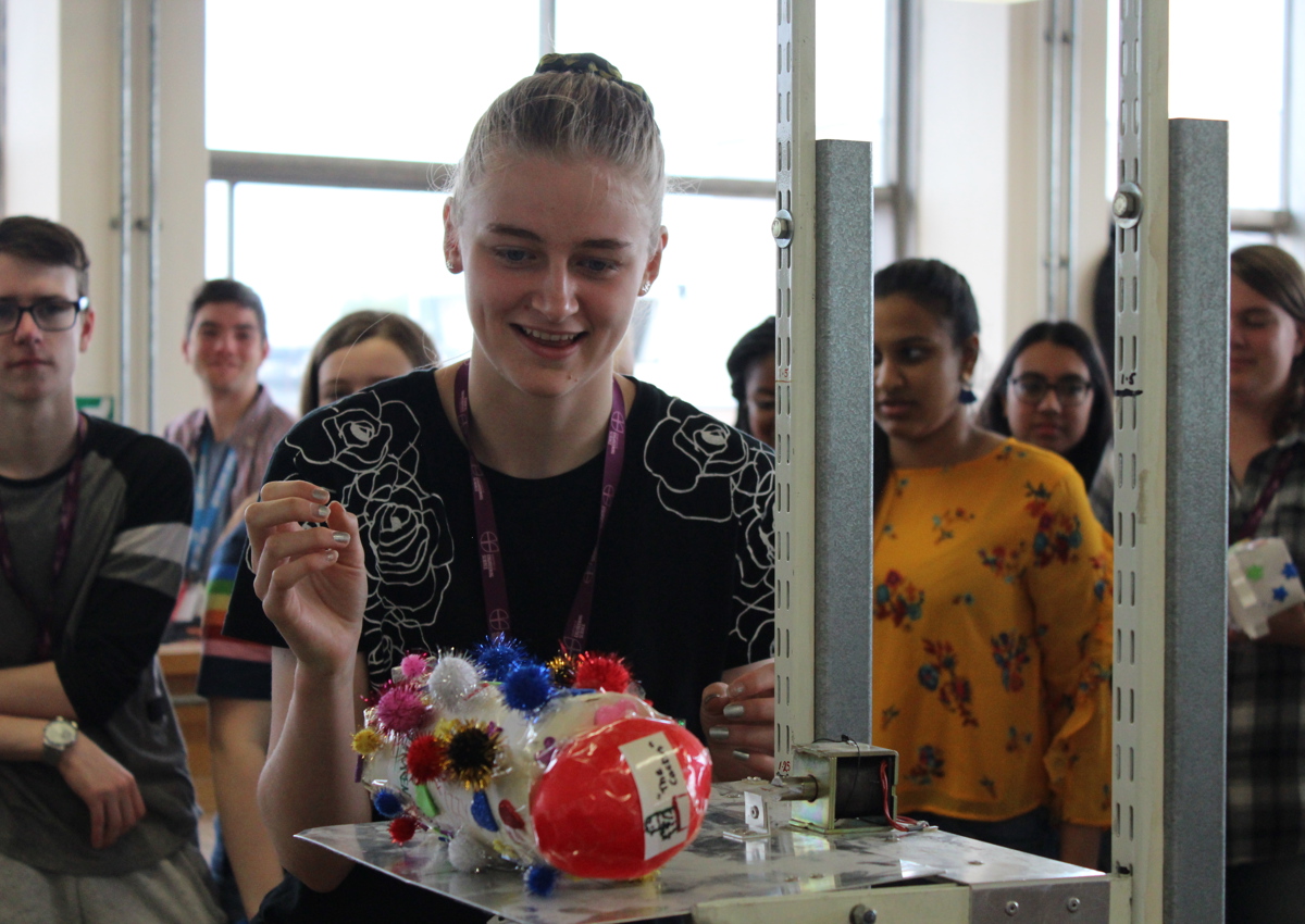 School student places handmade project on scales infront of classmates
