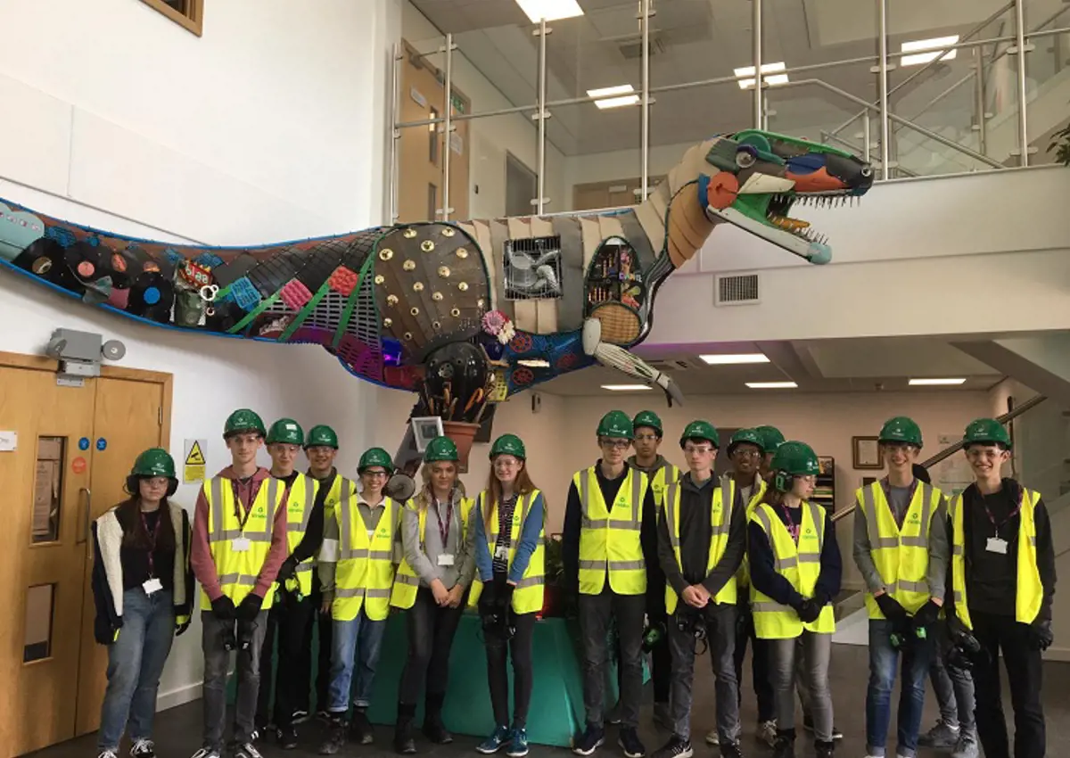 Group of school students in safety wear infront of a robot t-rex