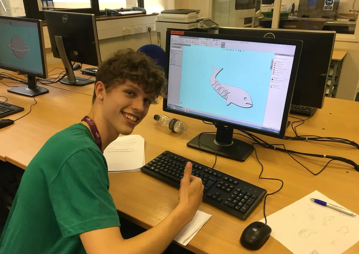Student sat at computer giving thumbs up to camera