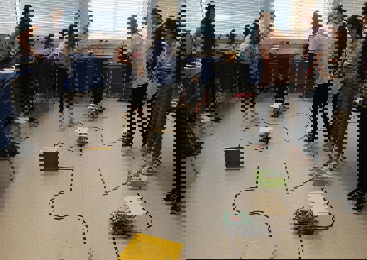 Group of students looking at many small robots