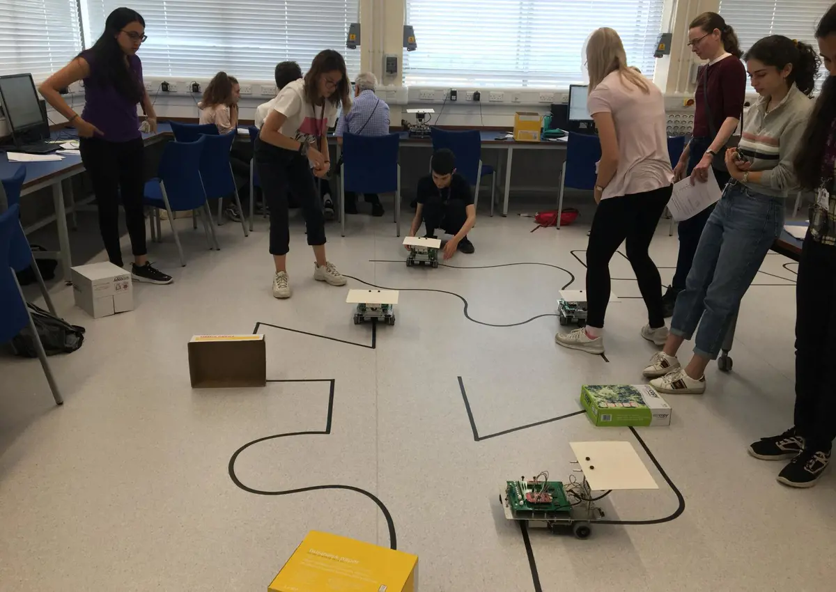 Group of students looking at many small robots