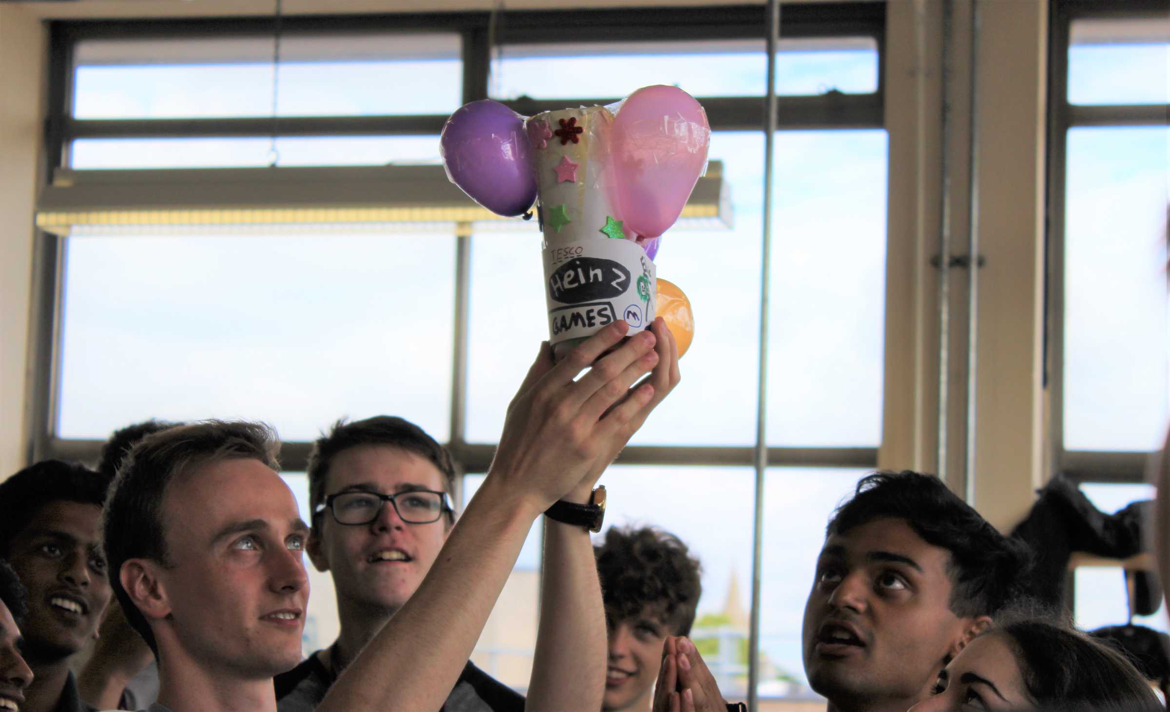 Group of school students, one holds up balloon project