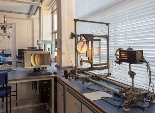 Lamp pointed at glass lens and screen showing light patterns