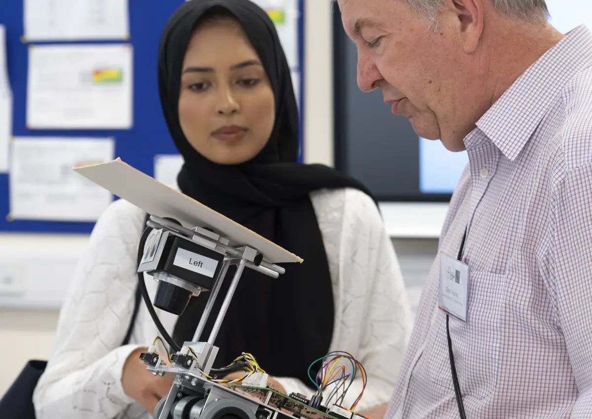 Older man holding and looking at robot