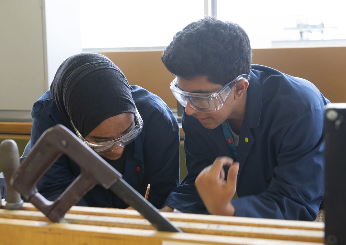 Two students at work in workshop with safety glasses on