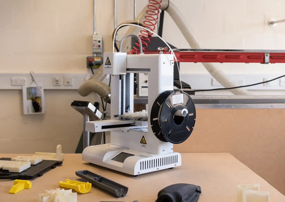 Tabletop 3D printer surrounded by plastic products