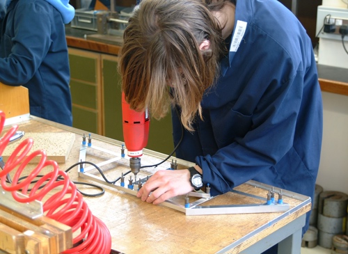 Student drilling into a metal frame bridge