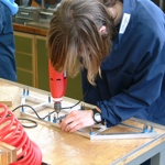 Student drilling into a metal frame bridge