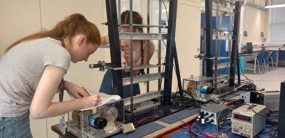 Two students working on machinery in a workshop