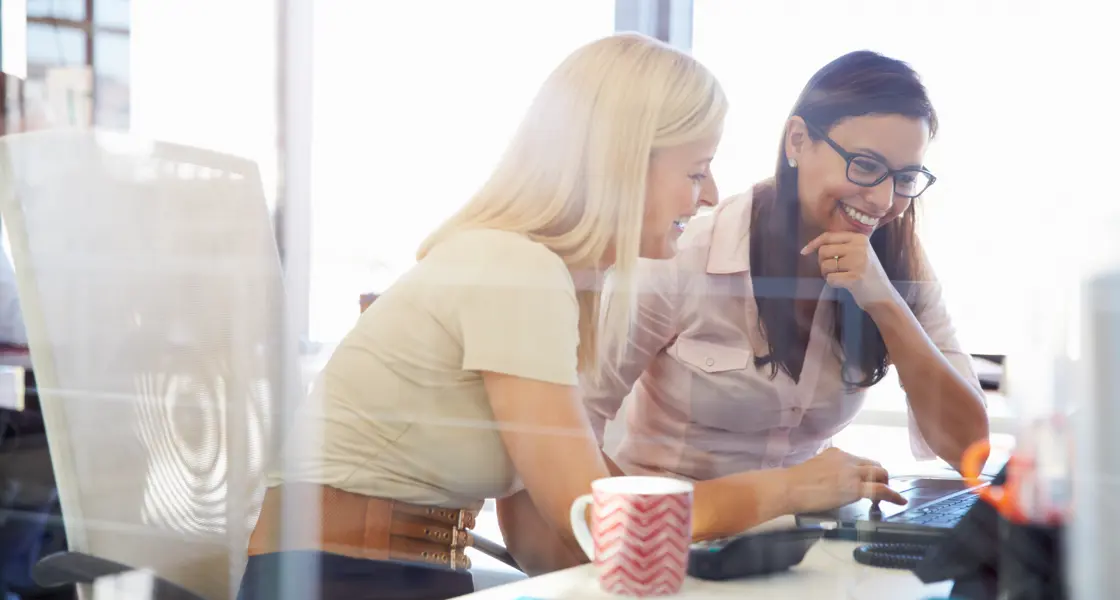 Two women working on laptop and smiling