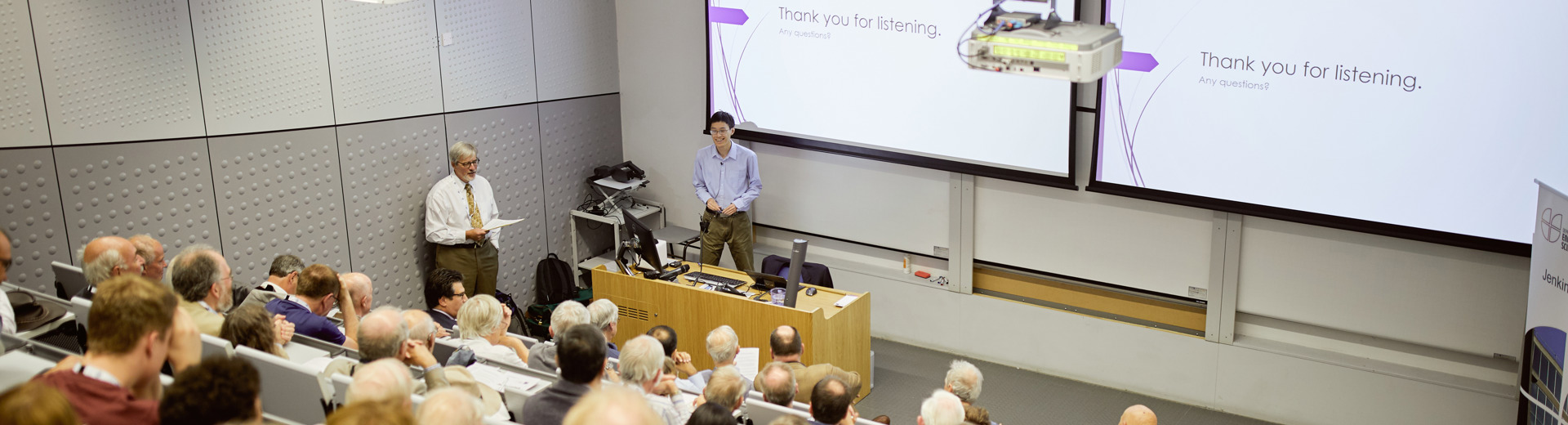 Wide view of a lecture hall filled with attendees listening to a presenter in Engineering Science.
