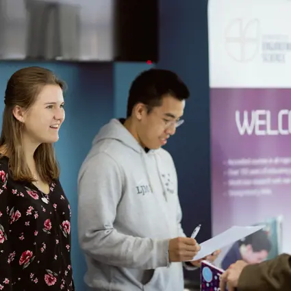Two student ambassadors greet guests at an event in the Thom Building