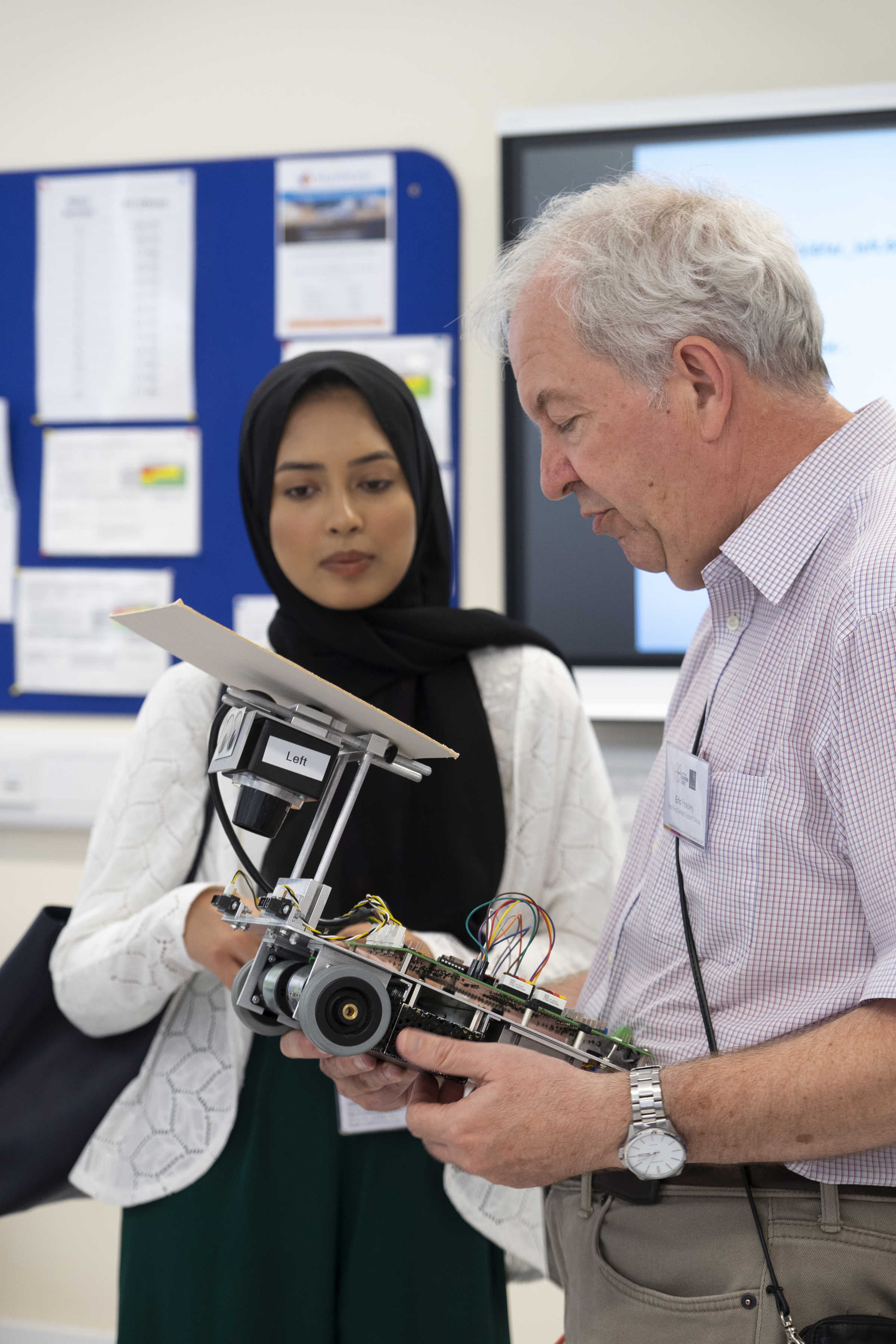 Older man holding and looking at robot