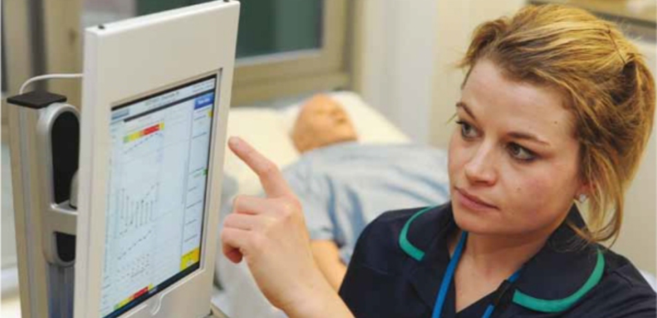 Nurse pointing at monitor with patient vital sign information