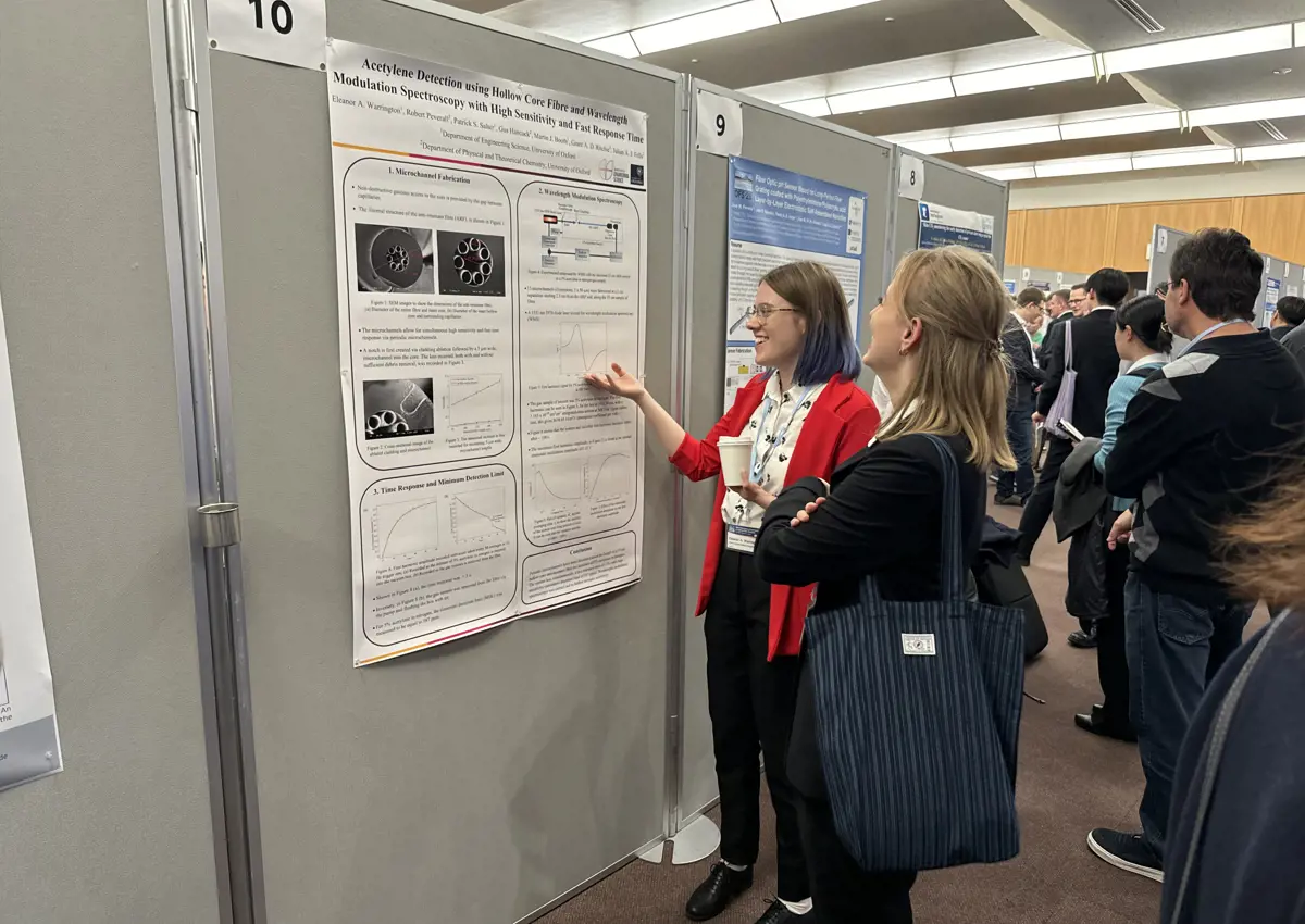 Eleanor Warrington Presenting: Eleanor, a white woman, is presenting their poster to another white woman.