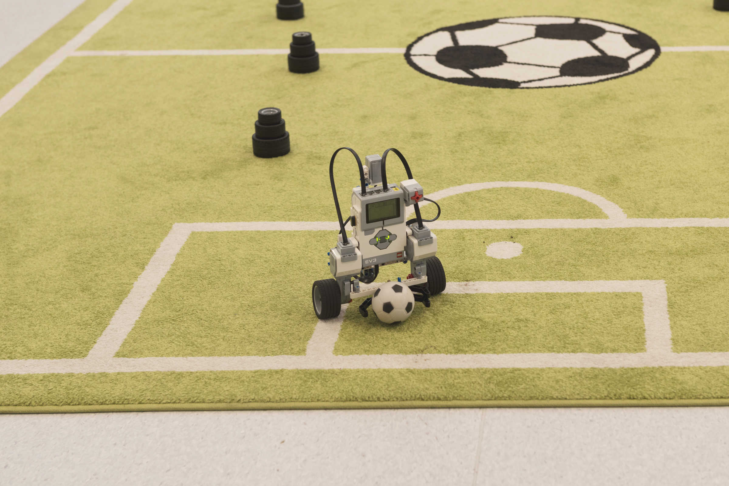 Small robot playing football on miniature football pitch