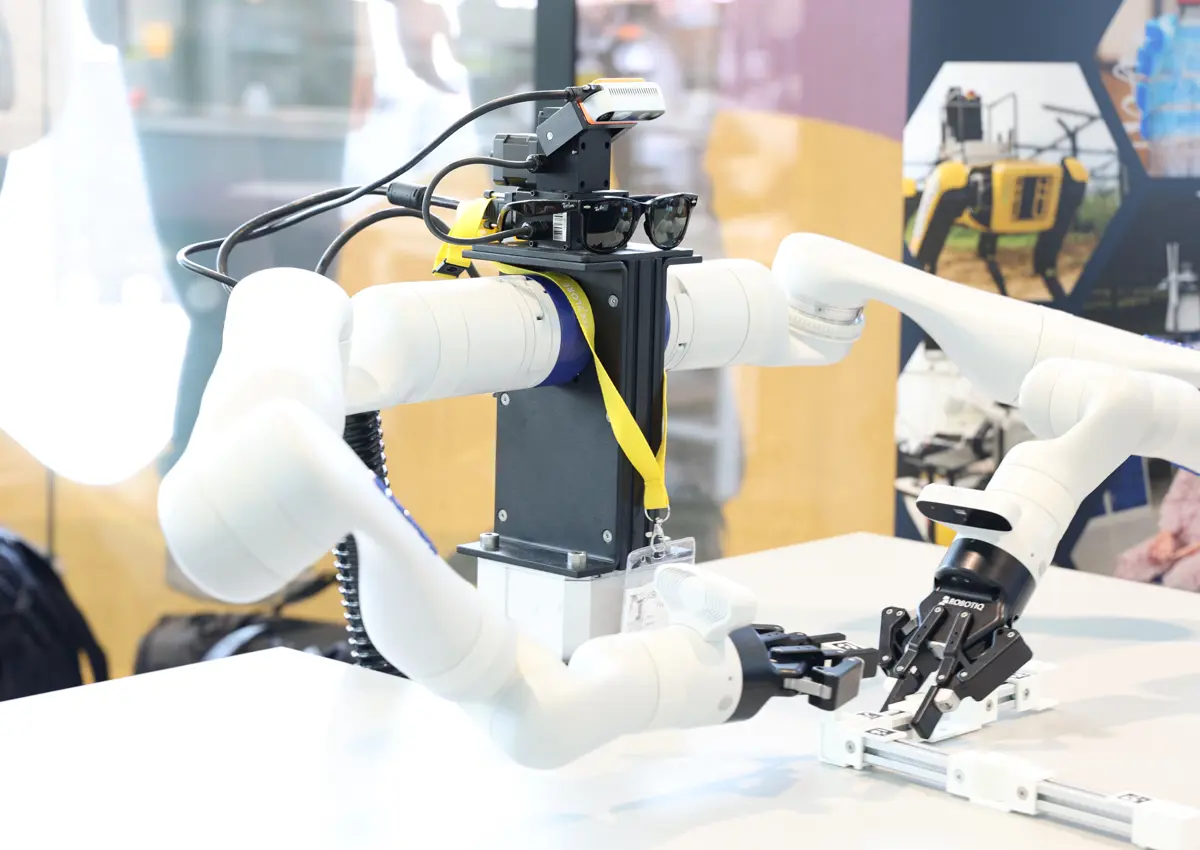 Close-up of Frank, a dual-arm robotic manipulator from the Oxford Robotics Institute, wearing novelty glasses. The robot’s articulated arms are partially raised, suggesting human-like posture and motion.