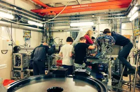 A photo of people working around a large machine in the lab