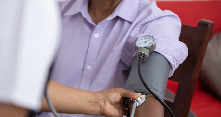 Nurse takes blood pressure of patient wearing mask
