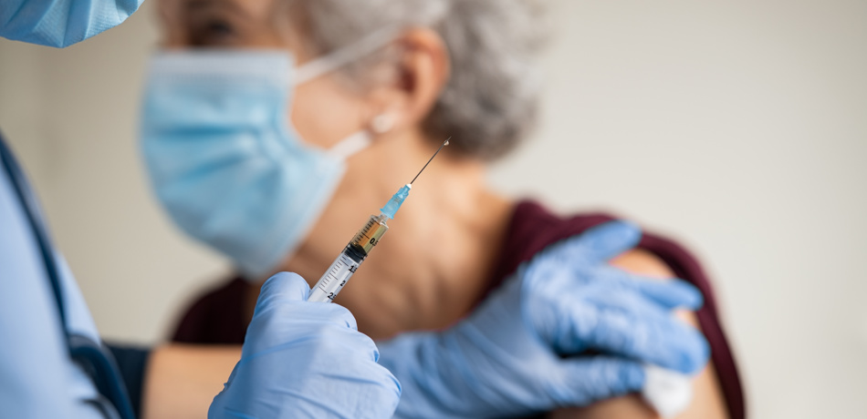 Doctor wearing PPE gives elderly woman a vaccine