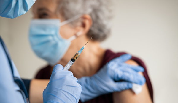 Doctor wearing PPE gives elderly woman a vaccine