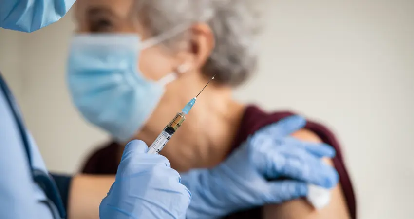 Doctor wearing PPE gives elderly woman a vaccine