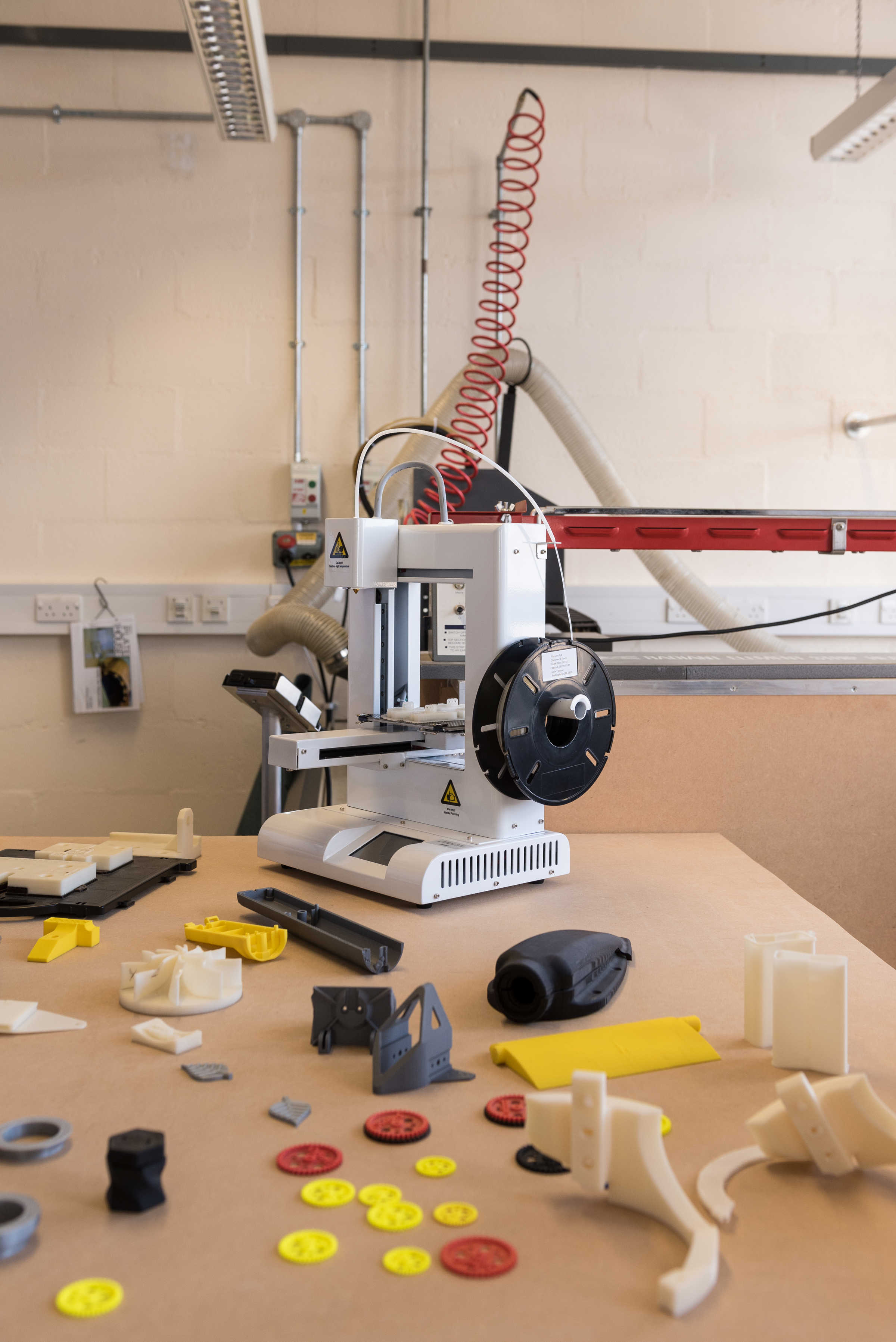 Tabletop 3D printer surrounded by plastic products