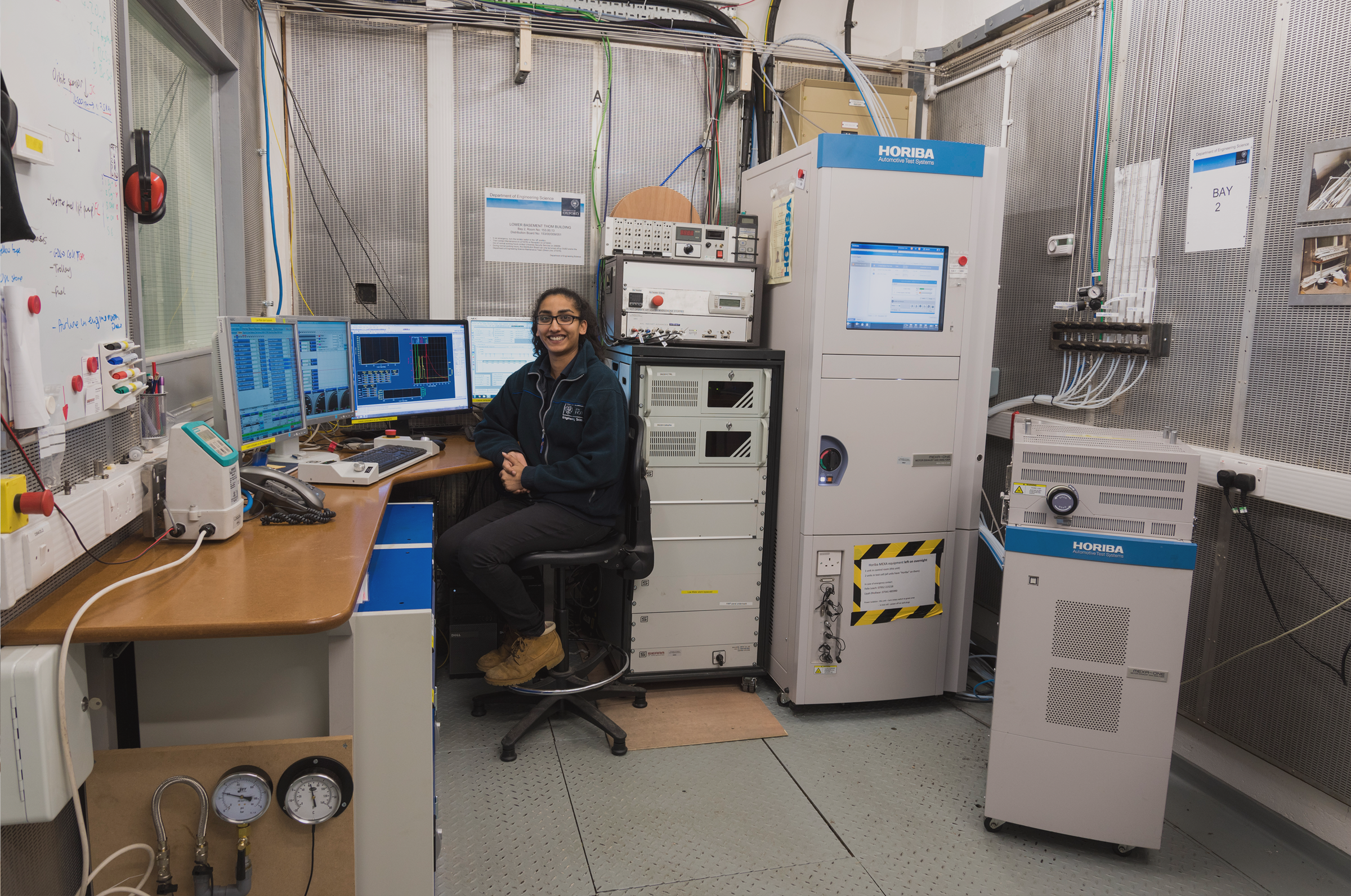 Smiling student alone at desk in big lab office space with computers