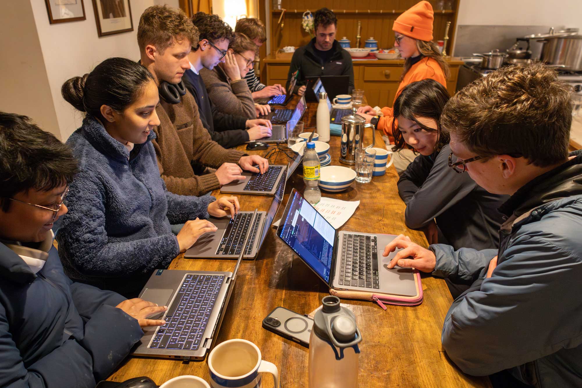 A group of researchers working on laptops around a wooden table inside the fort.