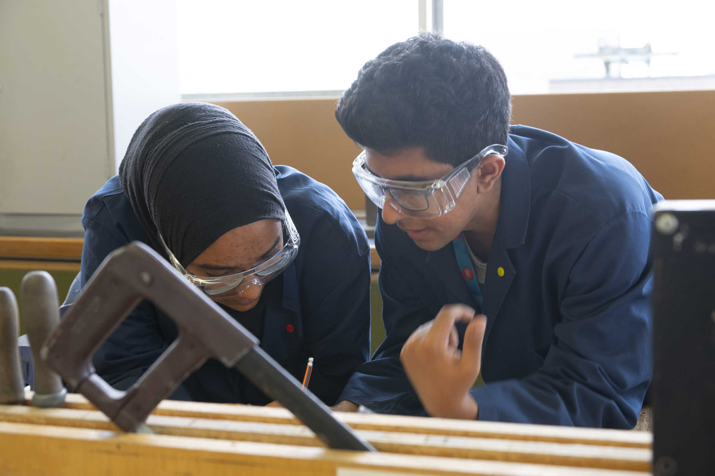 Two students at work in workshop with safety glasses on