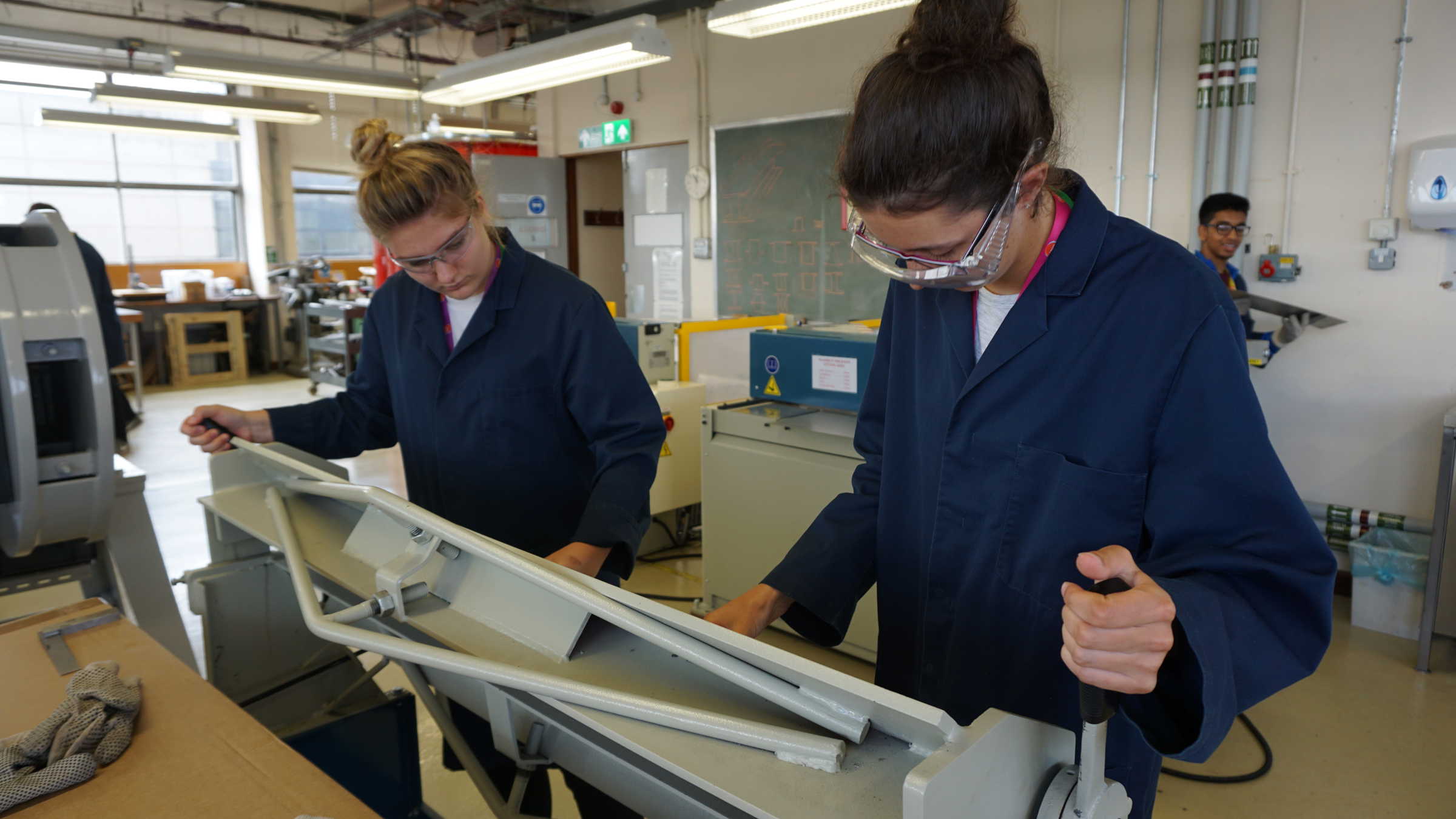 Two students in lab with labcoats and safety glasses