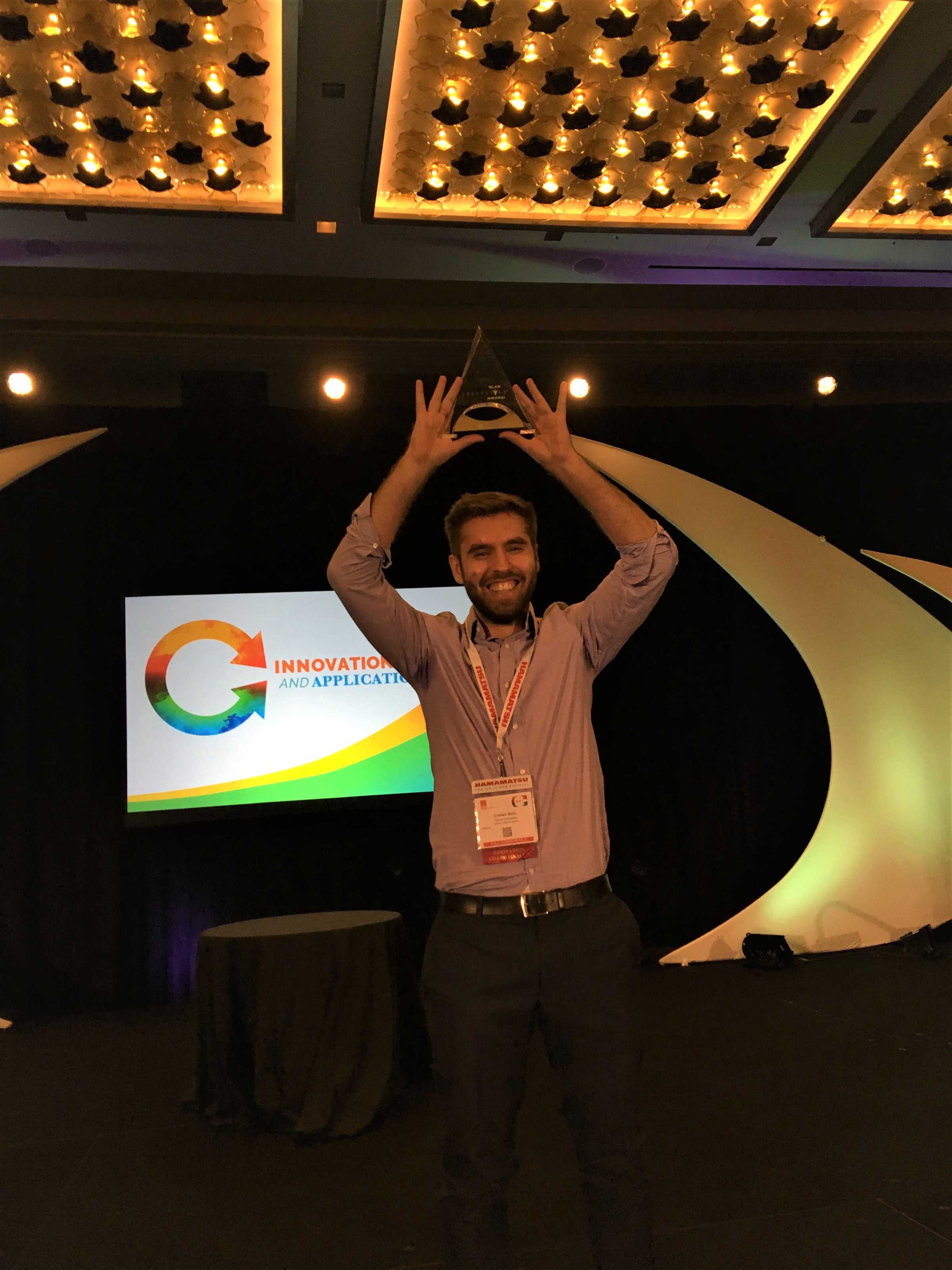 DPhil student Cristian Soitu holding aloft his trophy from the SLAS 2019 Conference