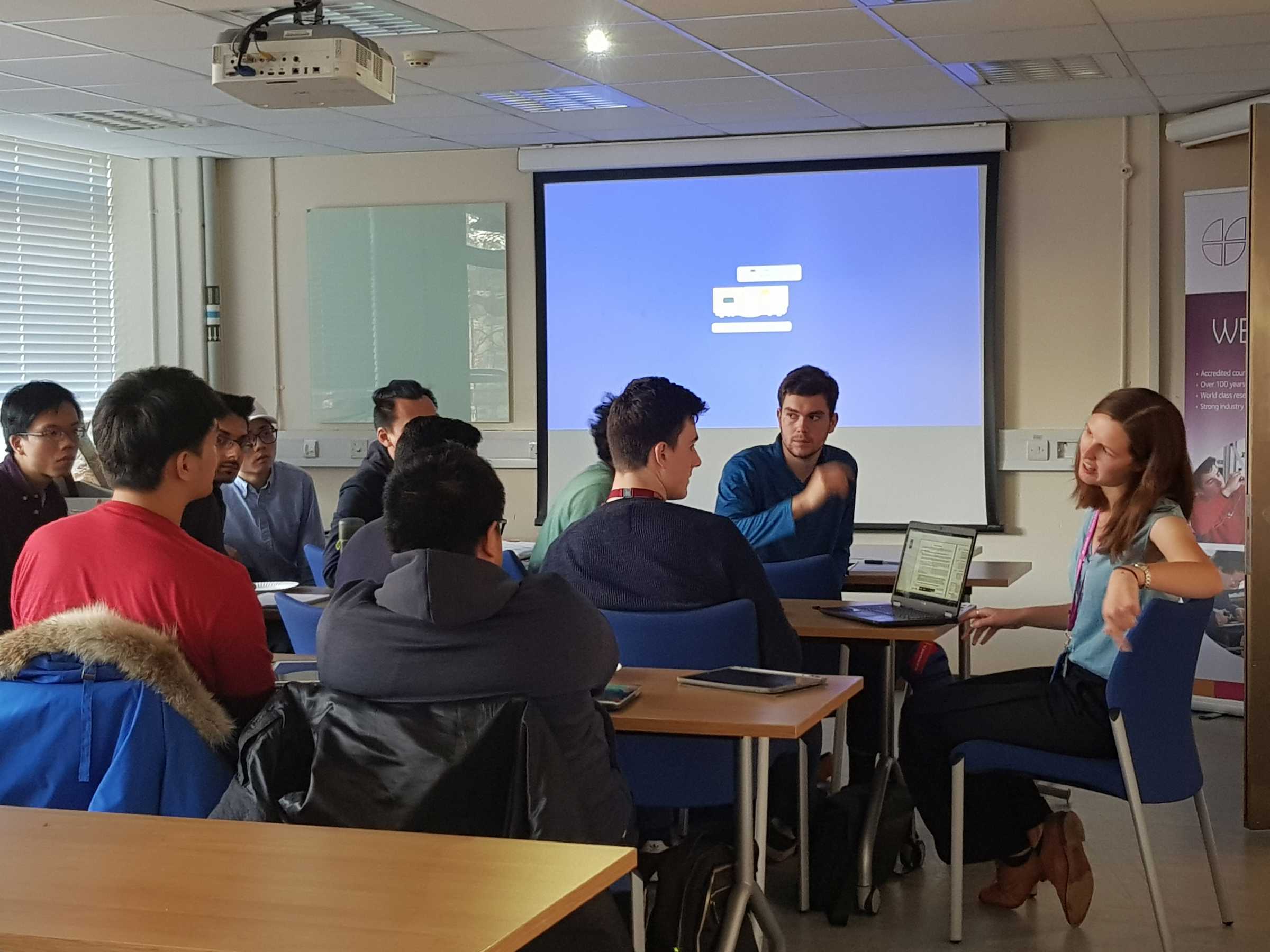 Group of students and teacher sat in classroom discussing
