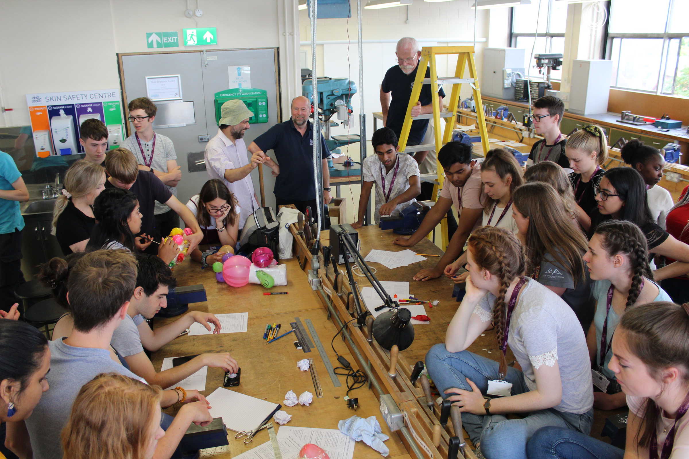 Large group of school students surrounding workshop benches