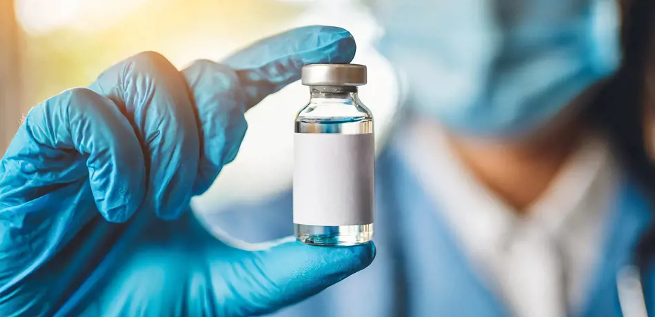 Stock image, scientist holding vaccine bottle in gloved hand