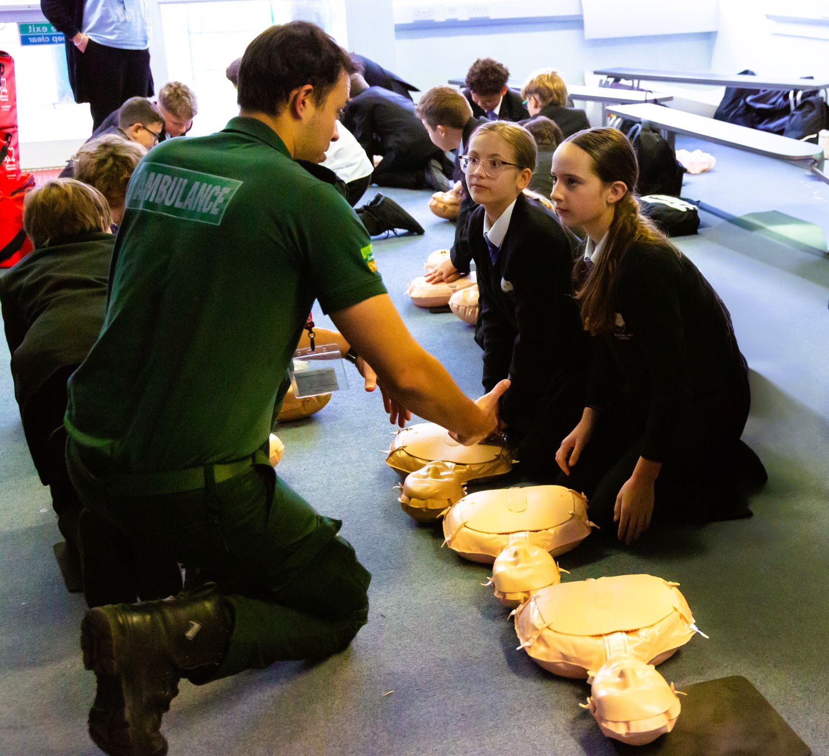 Man demonstrating CPR to Year 9 students in school setting