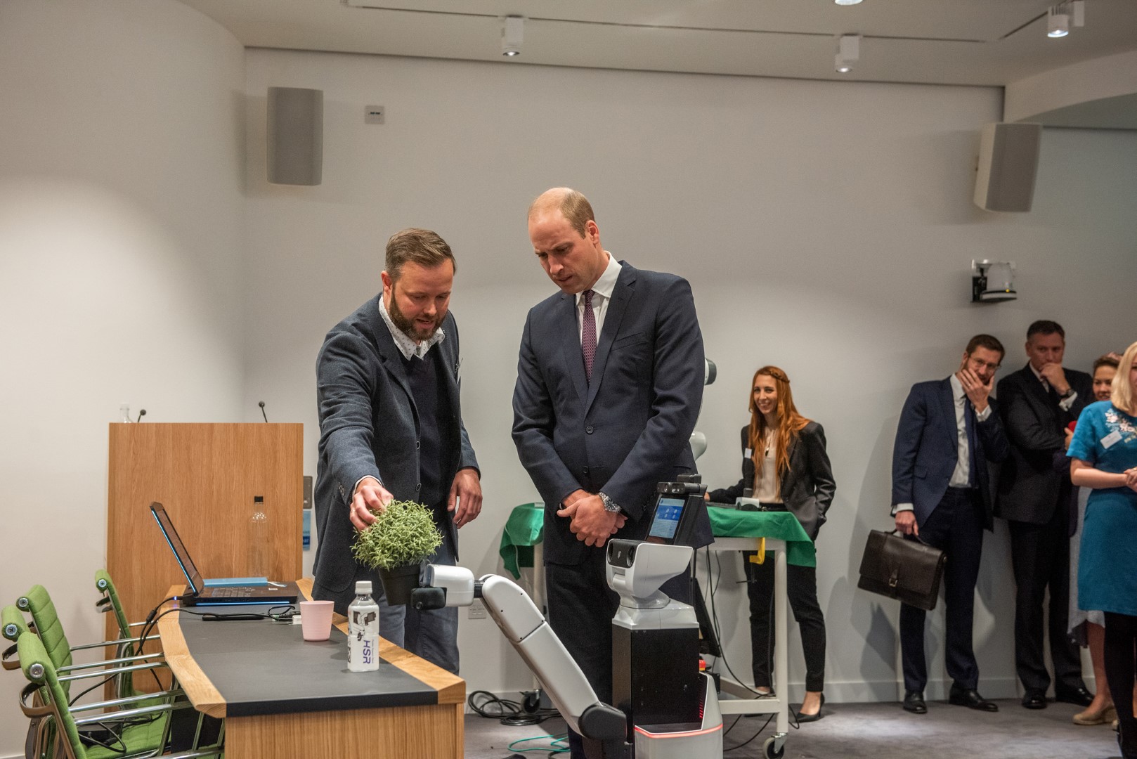 Duke Of Cambridge and Lars Kunze looking at the HSR Robot at Keble College. 